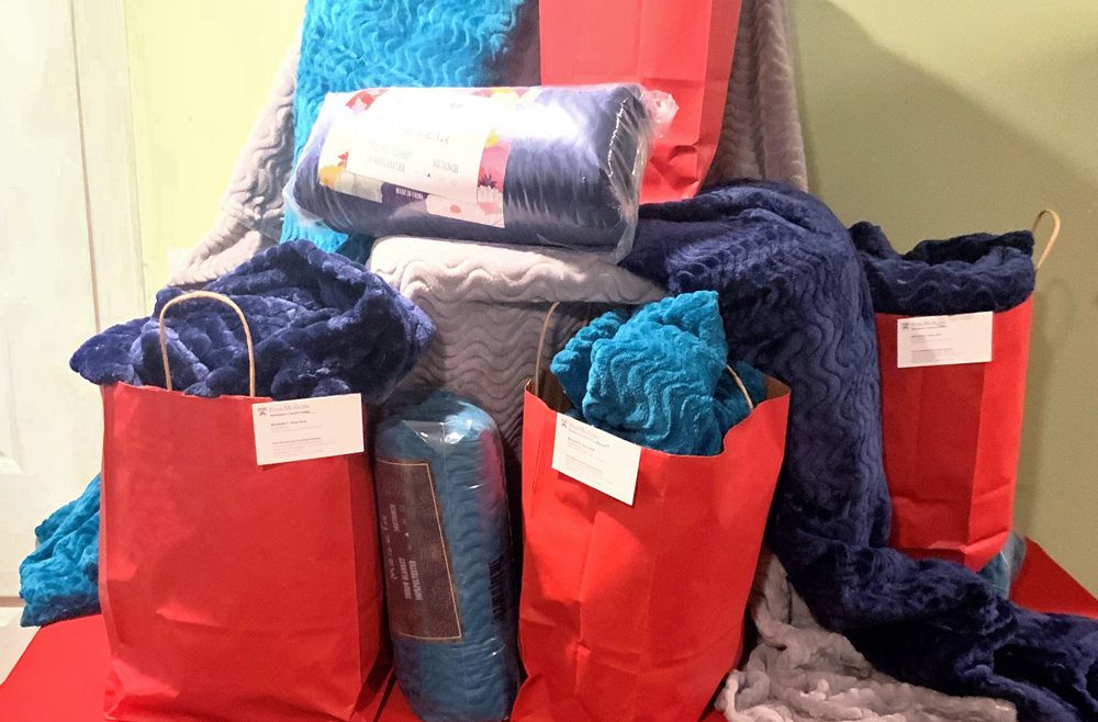 A table covered with new blankets, some in red paper bags 